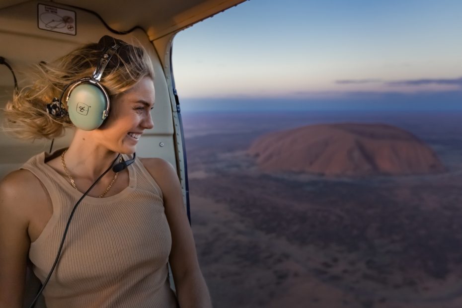 Woman looking out of helicopter over Uluru