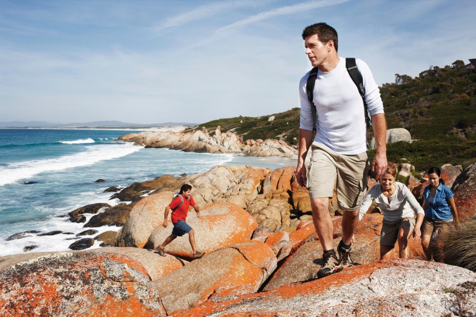 Hikers climbing rocks by the Bay of Fires