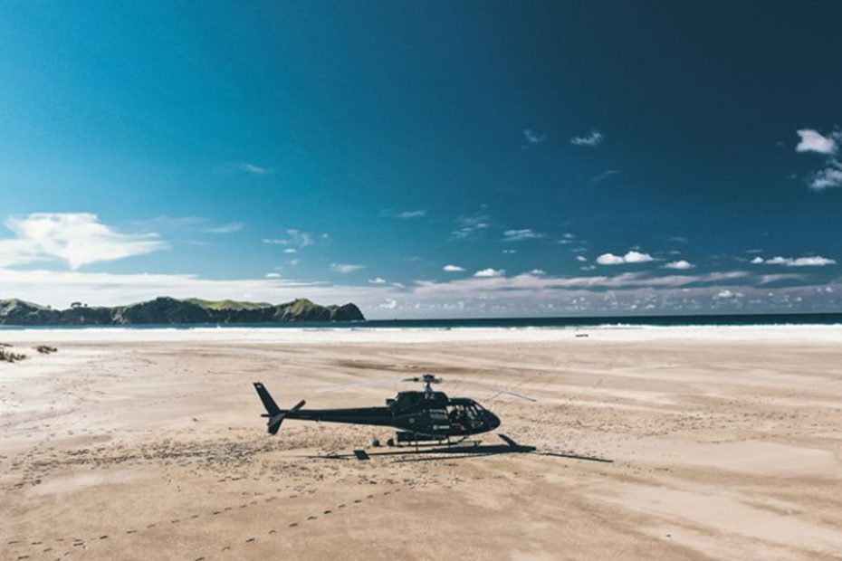 Helicopter sitting on a golden sand Great Barrier Island beach