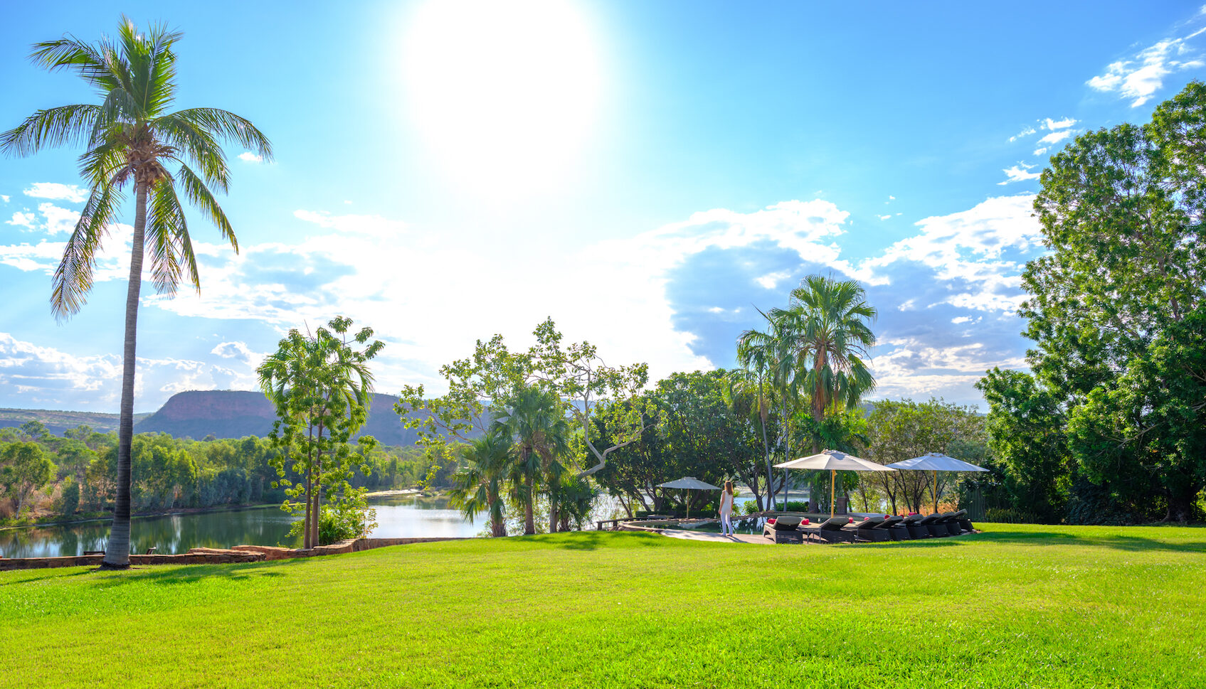 Grass leading to pool with palm trees at El Questro