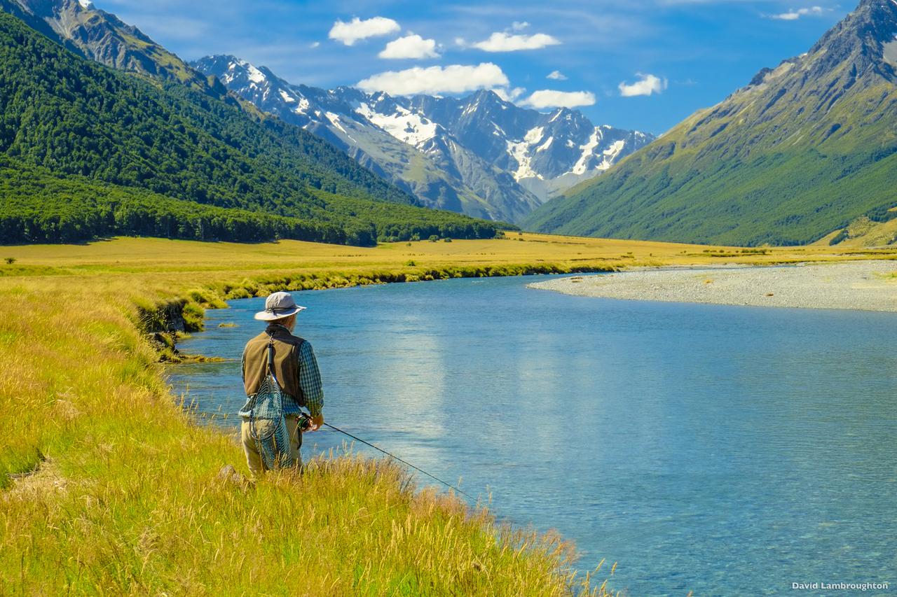 Man fly fishing on river with Southern Alps in the background