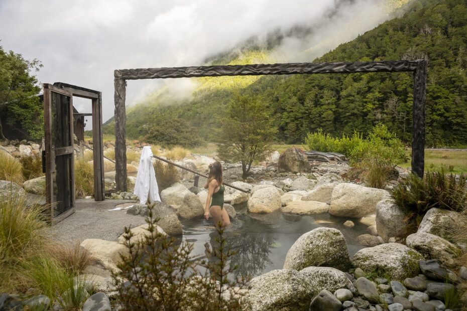 Lady bathing at Maruia Springs hot springs surrounded by mountains and forests