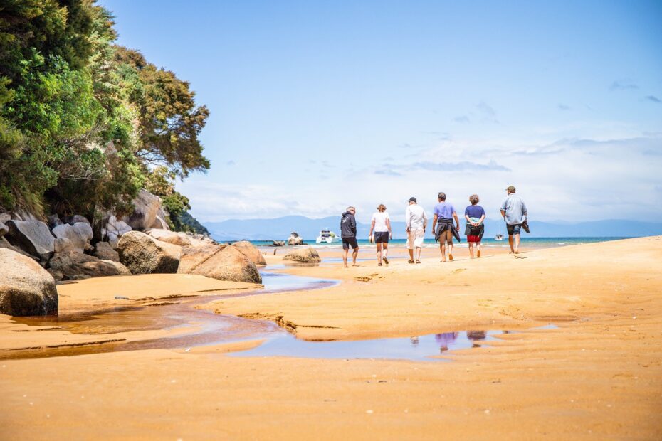 People walking on a golden beach in the Abel Tasman National Park