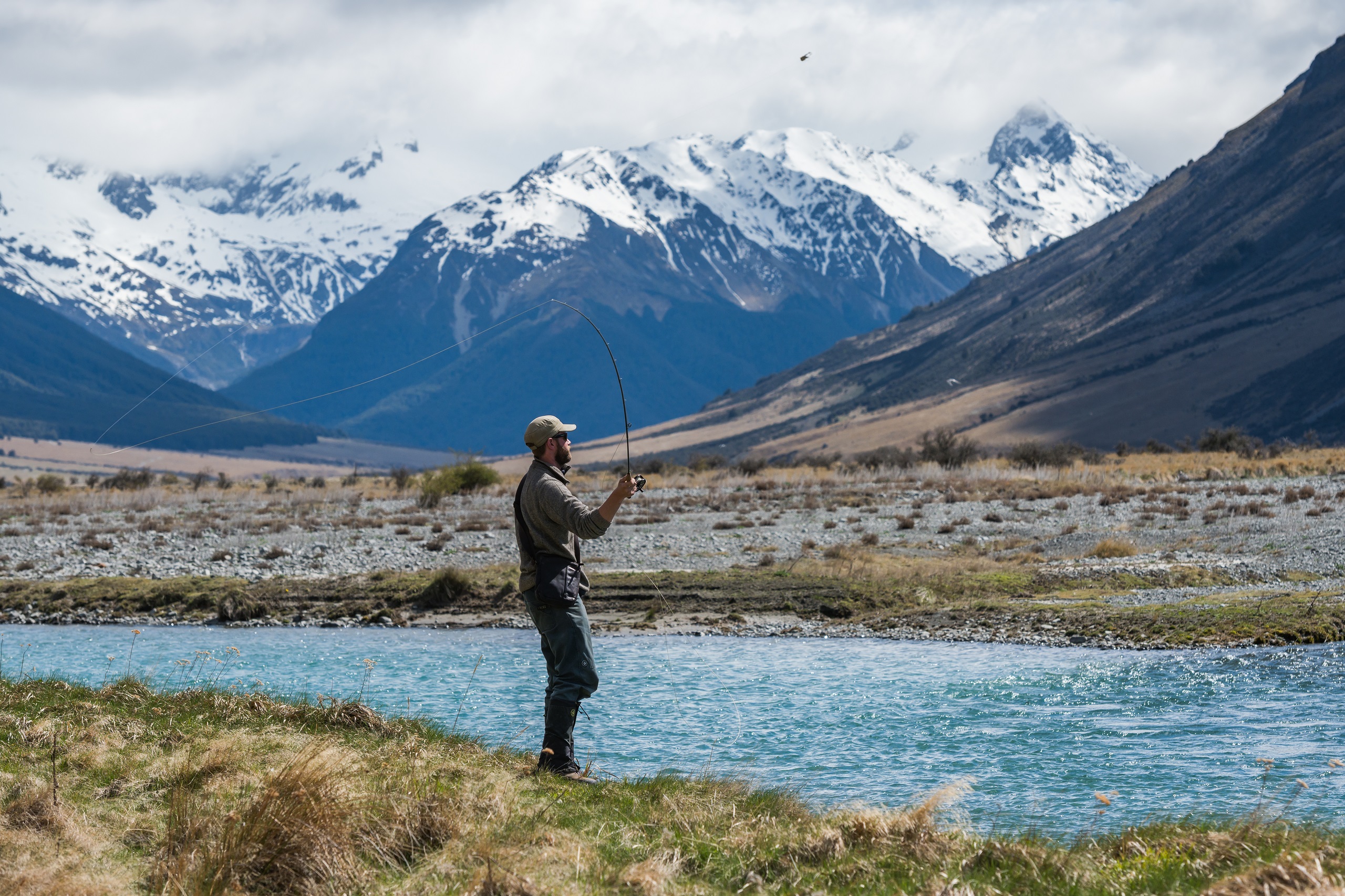 Man fly fishing on Ahuriri River with mountains in the background