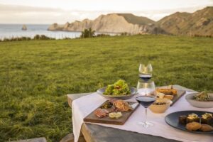 Table with food and wine in front of Cape Kidnappers