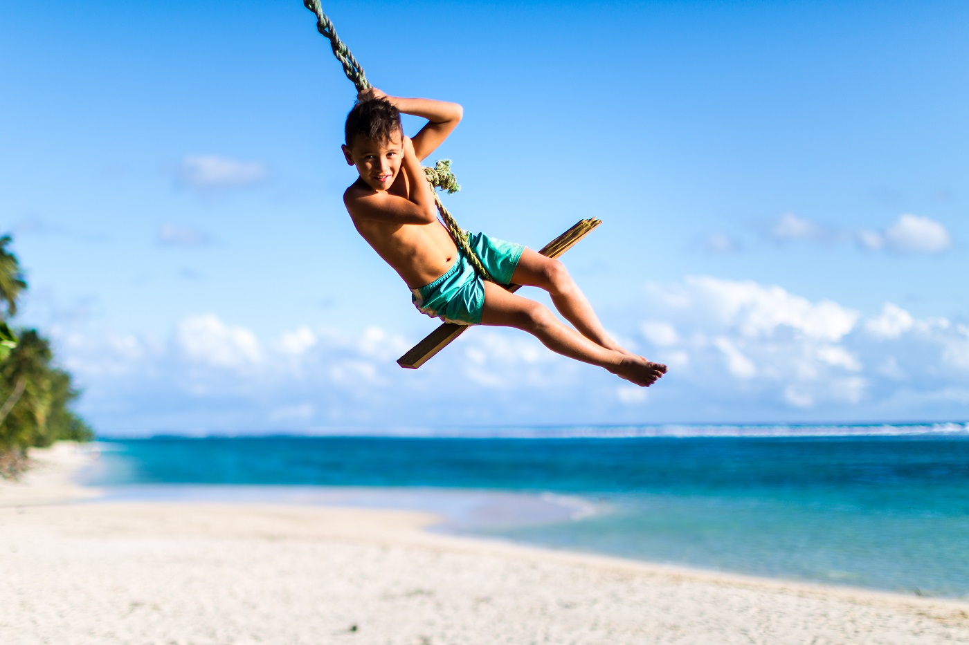 Young boy on a rope swing on Rarotonga beach