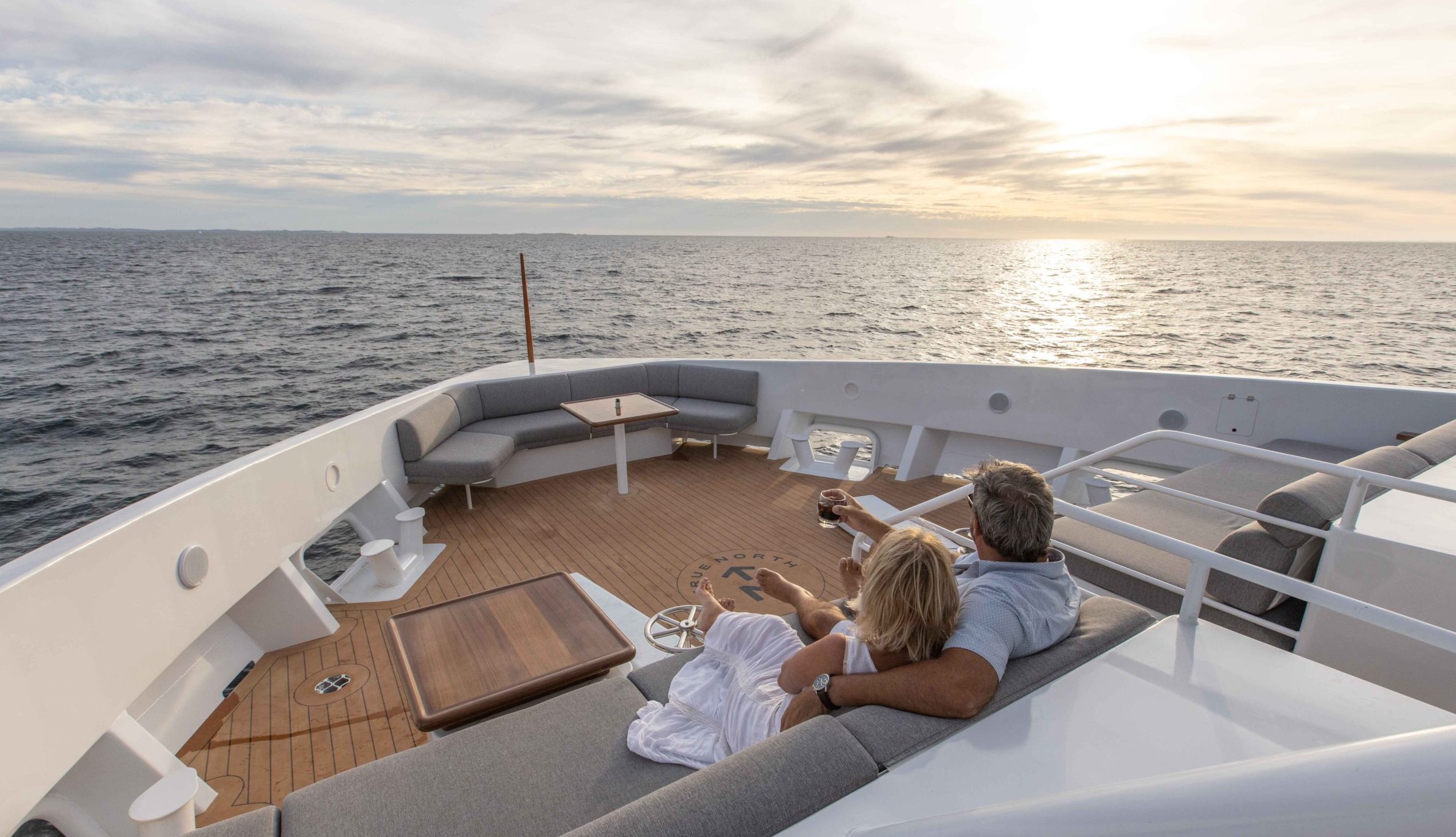 Couple enjoying a drink and the view on the bow of True North